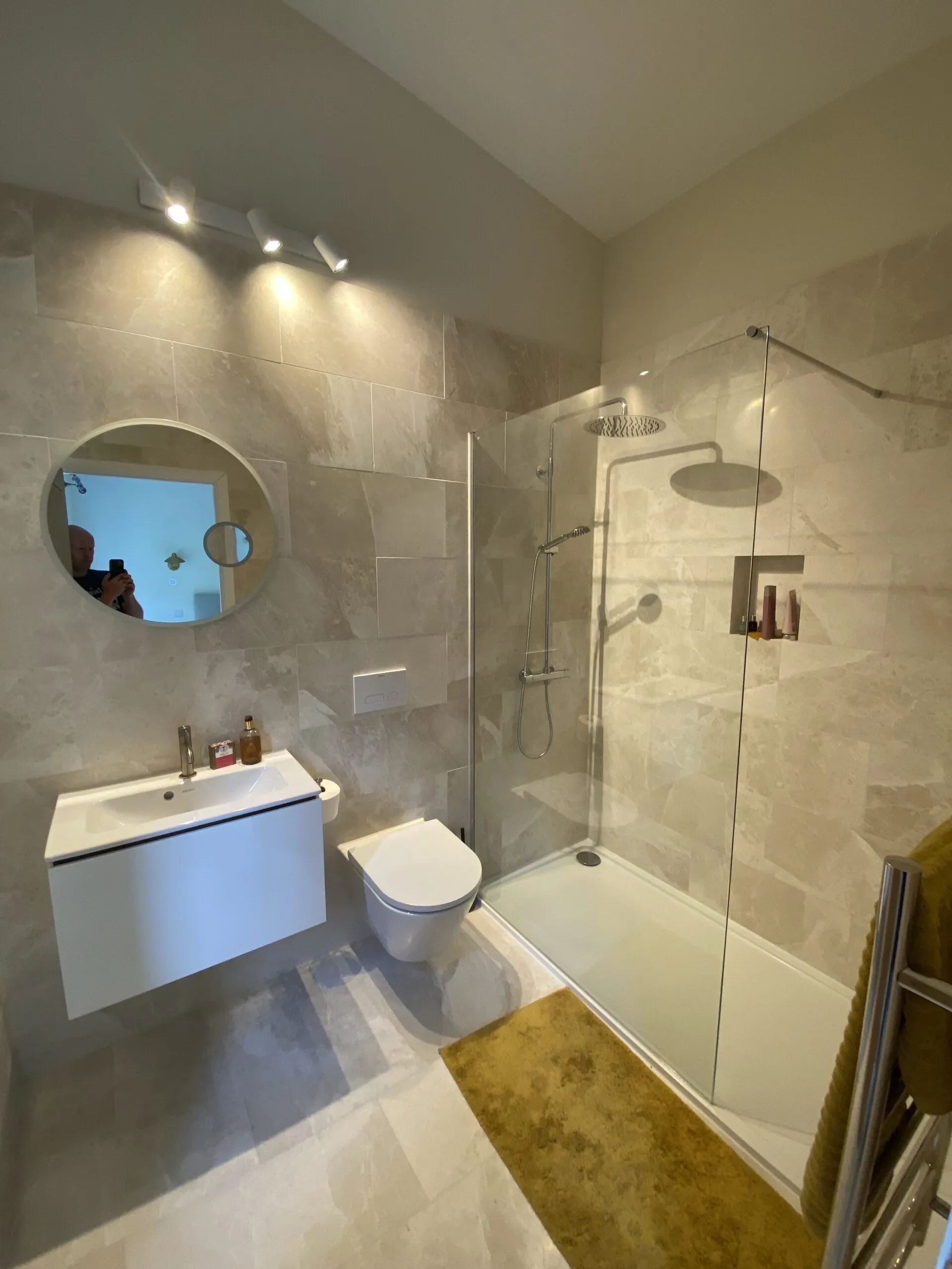 Large wall shower, concealed shower valve and wall mounted outlets. White wall hung vanity unit and toilet with concealed cistern.